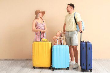 Little daughter with her parents and suitcases near beige wall