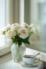 A cup of aromatic tea, a book and a rose on the table. May June July August.