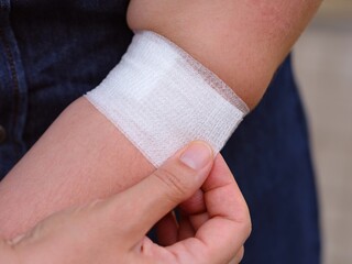 A woman putting a bandage on her hand after having blood taken