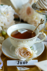 A cup of aromatic tea, a book and a rose on the table. May June July August.