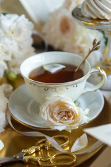 A cup of aromatic tea, a book and a rose on the table. May June July August.