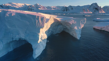 Large impressive iceberg cave in arctic sunset landscape. Huge high ice glacier at polar nature...