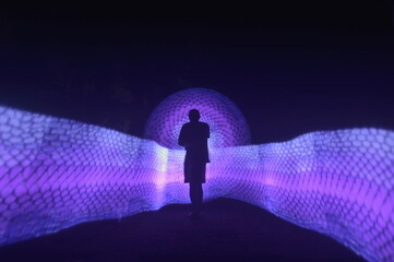 One person standing alone against a Colourful circle light painting as the backdrop