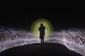 One person standing alone against a Colourful circle light painting as the backdrop	
