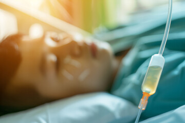 Fototapeta premium A serene scene capturing the close-up of an IV drip and blurred patient resting on a hospital bed, suffused with soft, golden sunlight streaming in.