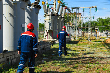 Electrician in a protective helmet inspects modern high-voltage equipment at a power plant