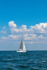 Obraz premium uWhite sloop rigged yacht sailing in the Baltic sea at sunset. Blye sky after the storm, soft sunlight. Transportation, travel, cruise, sport, recreation, leisure activity, racing, regatta