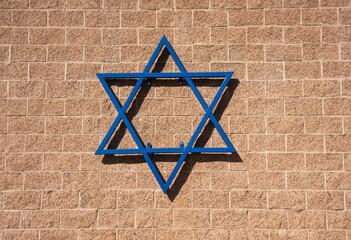 Blue Star of David on a brown brick wall in bright sunight