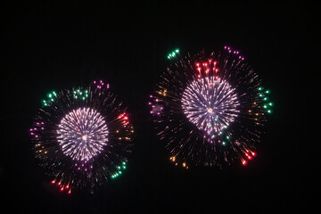 Japanese fireworks furing the firework festival. Fireworks on the dark sky background. Beautiful fireworks on the dark sky background in the city. 