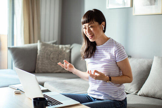 Smiling woman having a video call at home with a laptop and earphones