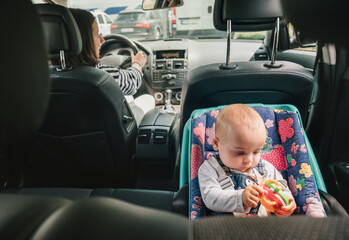 Portrait of baby in car seat while Mother driving a passenger car. Scene captures moment of care...