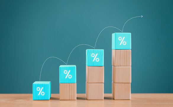 Inflation high, interest rate financial and mortgage rates concept. Wood block increasing with icon percentage symbol upward direction on blue background. Bank business analysis percent rate arrow up