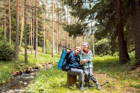 Father and daughter taking a break from hike and checking GPS on smartphone