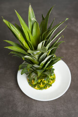 Fototapeta premium Pineapple leaves and fruit remains on a plate. Pineapple close-up on the table.