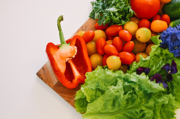 red sweet paprika on a wooden board along with other vegetables on a white background