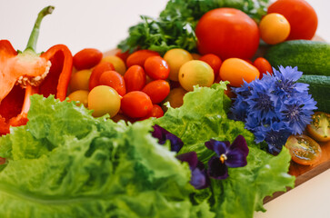 lettuce leaves on a wooden board along with red and green vegetables on a white background