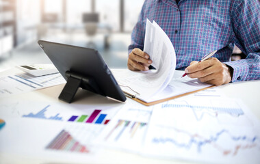 Businessman, investor using tablet working in office checking investment report and analyzing chart for investment plan
