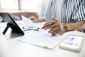 Asian man checking business documents using tablet to searching for information for start own business, concept for working at home, start new business