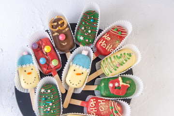 Christmas dessert. Sweet food. Cheesecake on a stick in the shape of ice cream. Children's treat in winter. Candy Christmas tree, snowman, deer and Santa Claus. Gingerbread cookies. White background.