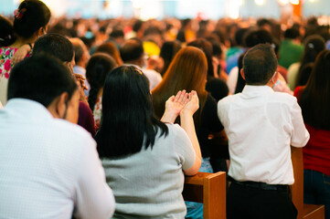 Woman folded hands and people pray in church during Friday Mass