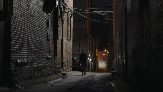 Man walking alone in downtown dark alley of city street 4k
