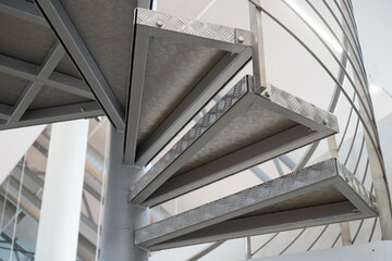 Obraz premium Close up of new modern spiral staircase indoors, stainless steel metal material. Wooden striped floor.