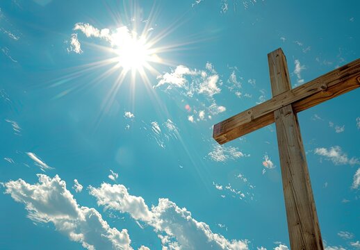 Wooden cross against a blue sky with clouds and sun.