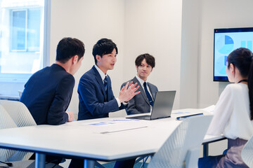 スーツを着て会議で話す若い男性