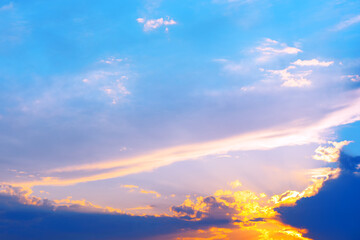 Sky is blue with a few clouds in the evening. The sun is setting and the sky is getting darker