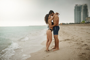 Fototapeta premium Hug, love or couple at sea on honeymoon with support on vacation, valentines day or holiday. Trust, care or man with embrace, peace or woman for bonding together at beach for romantic trip on sand
