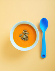 pumpkin soup with blue plastic spoon