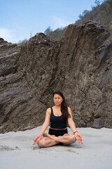 India, Rishikesh, March 27, 2024. Asian beautiful young woman does yoga near Ganges. High quality photo