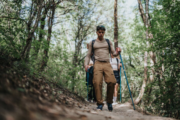 Obraz premium Group of friends hiking through a lush forest trail, showcasing their adventure and enjoyment of nature. Ideal for concepts of friendship, outdoor activities, and healthy lifestyle.