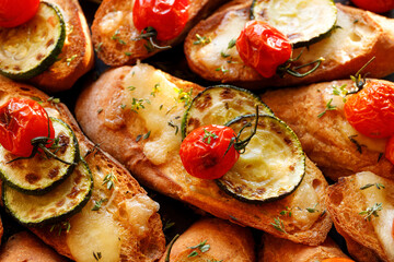 Sliced ​​baguette toasts with mozzarella cheese, zucchini and tomatoes sprinkled with fresh herbs, close up view
