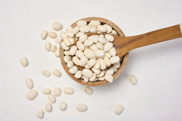 Raw white beans in a plate on the table, top view.