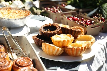 Tasty tartlets and other pastries on table outdoors, closeup