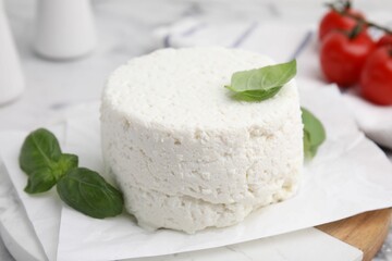 Fresh ricotta (cream cheese) and basil on light table, closeup