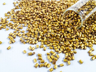 Gold color masterbatch granules with glass tube on white background.Color pigment carrier polymer...