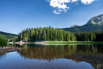 Der schwarze See oder Crno Jezero ist ein Gletschersee und ein Higlight in Durmitor in Montenegro, im Hintergrund die Berge mit Bäumen und Wald (Quer)