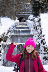 Winter hiking trails Pyrenees Huesca Artificial waterfall Canfranc Spain. Beautiful woman with her fist up in pink clothes.