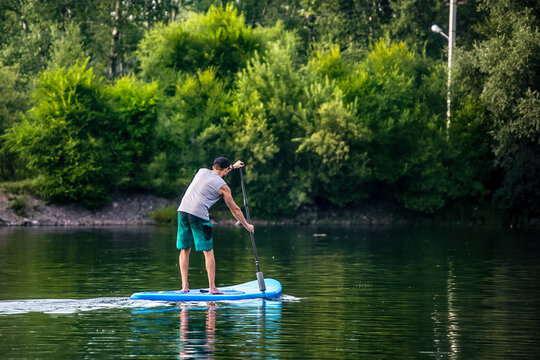 A man sup surfing paddling on a boat on the river in summer.