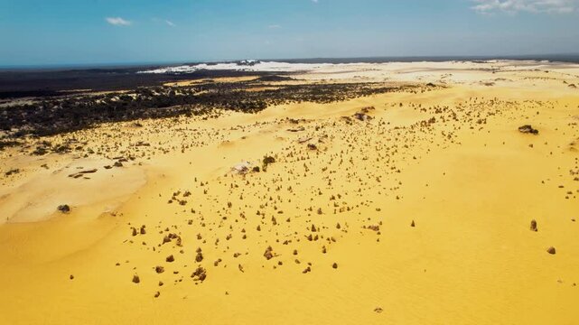 An aerial view of the Pinnacles Desert in Western Australia, showing the unique rock formations rising from the sand.