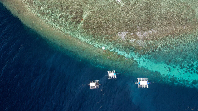 Breathtaking aerial view of Balicasag Island, Philippines showcasing local bankas amidst vibrant coral reefs teeming with marine life.