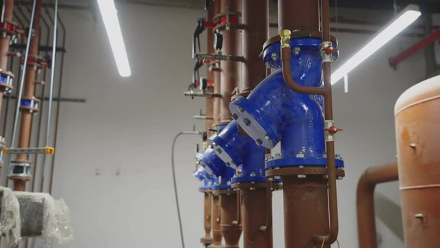 Row of vertically routed tubes with fittings and equipment. Operating fluid piping inside modern building.