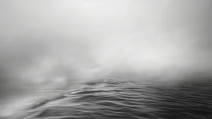 Calm black and white ocean scene with gentle waves under a misty sky. The soft gradients and fog create a serene and tranquil atmosphere