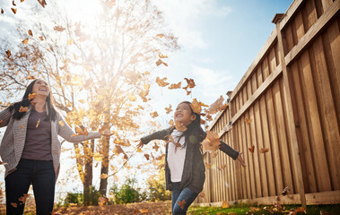 Kids, mother and girl throwing autumn leaves in garden of home together for bonding or love. Asian family, fall or smile with happy single parent and daughter having fun in backyard for wellness