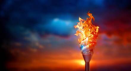 Blue and red flame is lit of a sport torch on sunset sky background. Concept of sports competitions and awards ceremonies