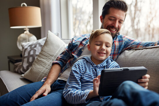 Man, child and tablet on couch with internet for educational gaming, movie bonding and online tv show. Family, father and son with digital tech in home in living room for relax, streaming and happy - Powered by Adobe
