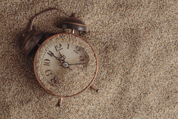 Vintage alarm clock on sand background. Top view with copy space.