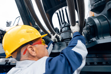 Professional mechanic diagnostics hydraulic hose system equipment on excavator to raise bucket.